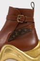 Detail of brown leather ankle boot with gold sole, ankle buckle strap with Louis Vuitton logo s…