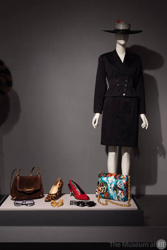 Azzedine Alaïa skirt suit, circa 1985, and Frank Olive hat, circa 1983, with accessories by Gucci, Robinson, Manolo Blahnik, Charles Jourdan, Gianni Versace, and unidentified designer, circa 1973-1990