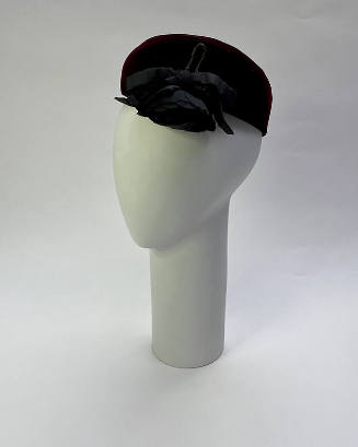 Black bumper crown beret with black rose over left eye
