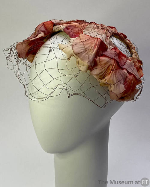Sculptured hat made of purple and pink rose petals with black net face veil