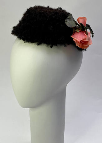Small black faux lamb fur hat with attached pink rose and green leaf ornament