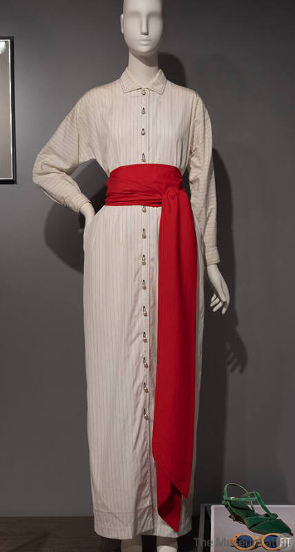 Long, off white button down dress with plack pinstripes and red sash tied at waist