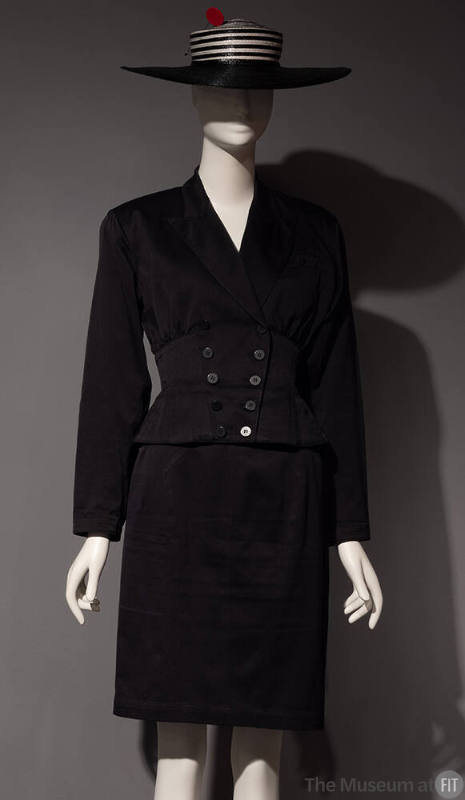 Black suit jacket and knee length skirt styled with black and white striped hat