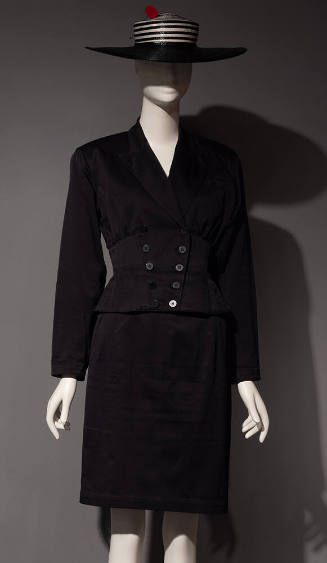 Black suit jacket and knee length skirt styled with black and white striped hat
