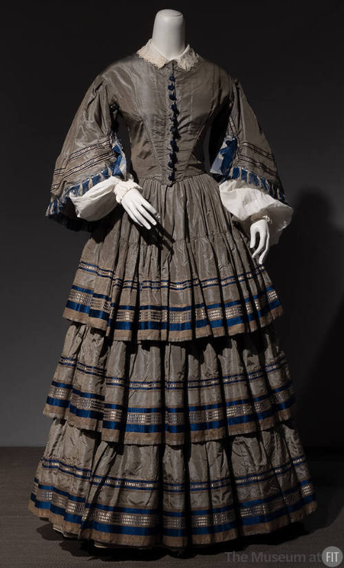 Grey silk taffeta floor length dress with bell sleeves and full pleated skirt with three ruffle…
