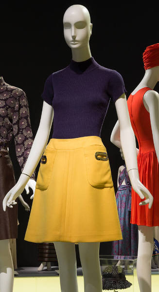 Navy blue short sleeved mock neck sweater and yellow mini skirt with large pockets at both hips