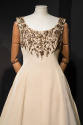 Detail of beige silk sleeveless dress with gold floral embroidery at round neckline and bust