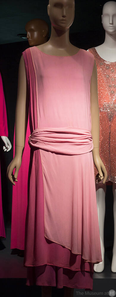 Pink tunic style sleeveless evening dress with attached dropped waist cummerbund, left side pan…