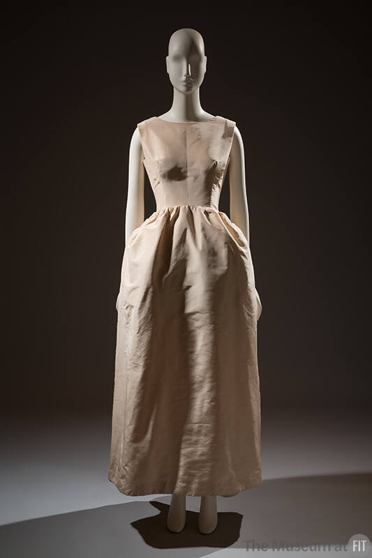 Sleeveless ivory dress with fitted bodice and long straightline skirt gathered at curved drop w…