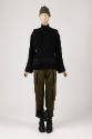 Black cable knit vest over long sleeve black top with hem fringe, green cargo pants, black leat…
