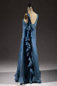 Back view of blue sleeveless dress with bow and row of ruffles down the side 