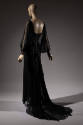 Back view of black silk floor length dress with sheer long dolman sleeves, skirt train 