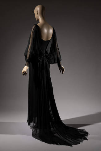 Back view of black silk floor length dress with sheer long dolman sleeves, skirt train 