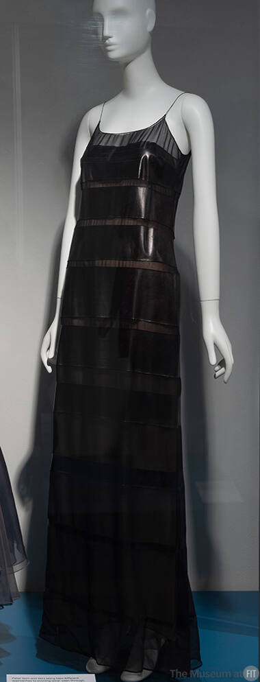 Black semi sheer slip style evening dress with horizontal bands of leather in various widths fr…