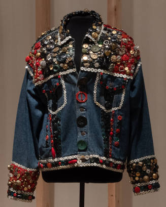 Blue denim long sleeve jacket covered with multicolor buttons at shoulders, cuffs and waistband…