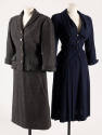 Dark grey suit with button front jacket and calf length straight skirt next to navy blue suit w…