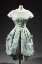 Light blue knee length evening dress with cap sleeves and large bubble overskirt draped on both…