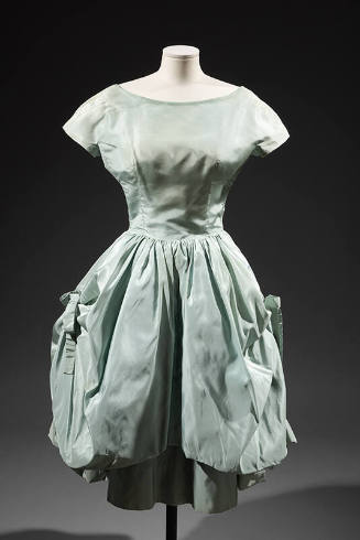 Light blue knee length evening dress with cap sleeves and large bubble overskirt draped on both…