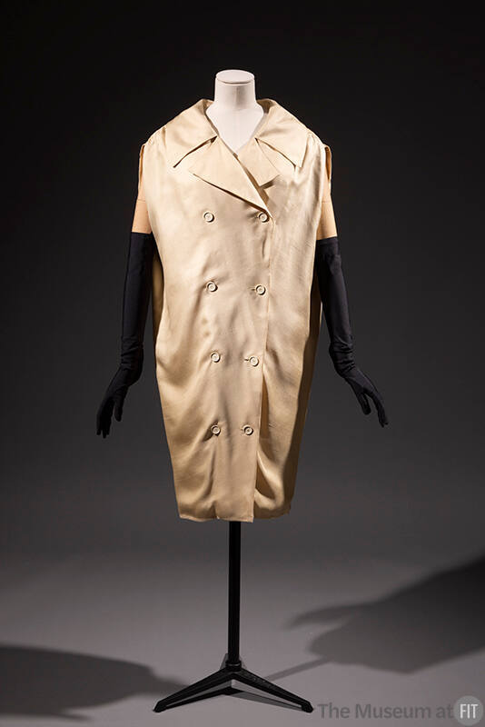 Cream double breasted sack style coat dress with wide lapels and dressed with black elbow lengt…
