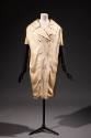 Cream double breasted sack style coat dress with wide lapels and dressed with black elbow lengt…