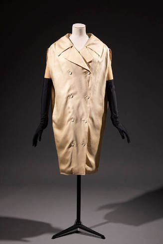 Cream double breasted sack style coat dress with wide lapels and dressed with black elbow lengt…