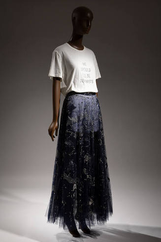 White t-shirt that reads We Should All Be Feminists, blue floor-length skirt with silver metall…