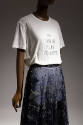Detail of white t-shirt that reads We Should All Be Feminist and blue skirt with silver metalli…