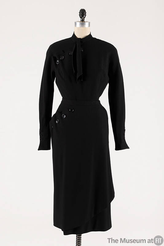 Black wool long sleeve top with asymmetric buttons at shoulder and neck tie, matching below-the…