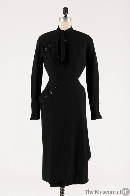 Black wool long sleeve top with asymmetric buttons at shoulder and neck tie, matching below-the…