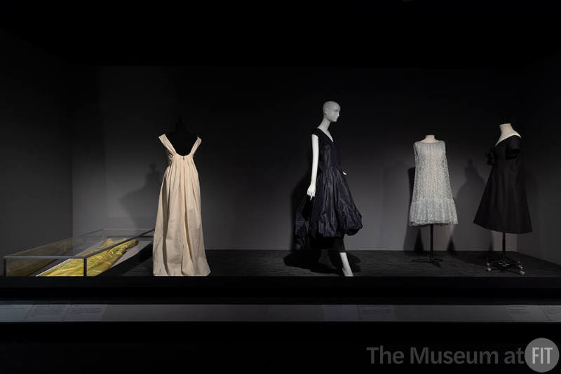 Dior + Balenciaga, Left to right: 83.159.1 (evening dress in case) and muslin copy,  IL2022.3.1 (black silk culottes), 91.255.1 (pale blue dress), 71.213.30 (black dress)