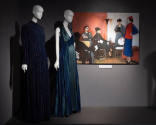 Designing Women exhibition installation view of two mannequins in a blue floor length coat and …