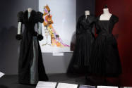 Designing Women exhibition installation view of three mannequins in black dresses with an image…