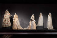 Designing Women exhibition installation view of five mannequins in ivory and beige floor length…