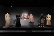 Designing Women exhibition installation view of five mannequins in dresses and a cape with a ph…