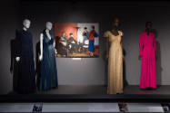 Designing Women exhibition installation view of four dressed mannequins with an image of a desi…