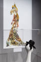 Designing Women exhibition installation view of a small black hat in a case and an image of a d…