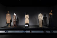Designing Women exhibition installation view of five dressed mannequins on a dimly lit platform…