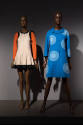 Designing Women exhibition installation view of two mannequins in a beige and orange mini dress…
