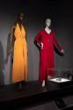 Designing Women exhibition installation view of two mannequins in an orange pants set, a red fl…