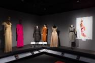 Designing Women exhibition installation view of six dressed mannequins on a platform and an ima…