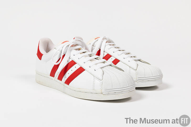 Pair of white sneakers with three red stripes on either side, white molded rubber toe cap and w…