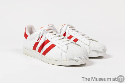 Pair of white sneakers with three red stripes on either side, white molded rubber toe cap and w…