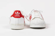 View of sneakers side by side showing rear red logo with white Adidas symbol and name on the le…