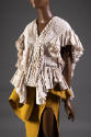 Detail of off-white pleated ruffled short sleeve jacket and dark yellow dress with thigh-high s…