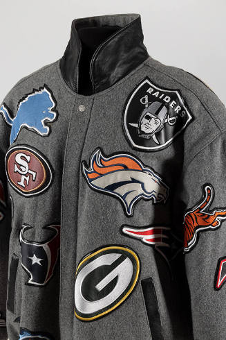 Detail of varsity jacket with allover football team patches, snap front, black leather collar