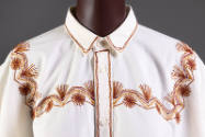 Detail view of muslin poncho style top showing collar, button front and red and brown embroider…