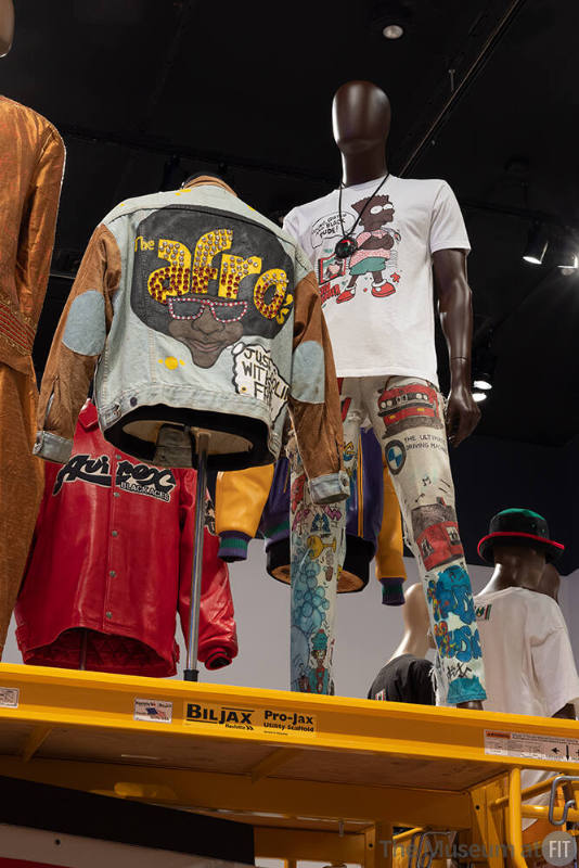 April Walker custom jacket for The Afros, 1989-1990, Courtesy of April Walker for Walker Wear; Custom jeans and leather pendant worn by Alphonso McClendon, 1989 with “Black Bart” T-shirt, circa 1989, Lent by Alphonso McClendon © The Museum at FIT
