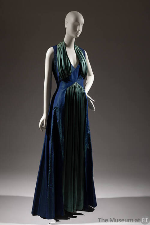 Sleeveless floor-length blue and green evening dress with deep V-neck framed with a collar of s…