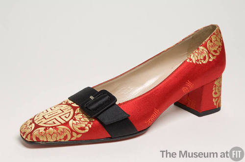 Red evening pump brocaded with red and gold Chinese inspired motifs, black belt across vamp and…