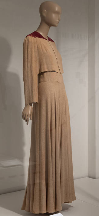 Floor-length beige evening dress and matching long-sleeved bolero with maroon detail at shoulde…